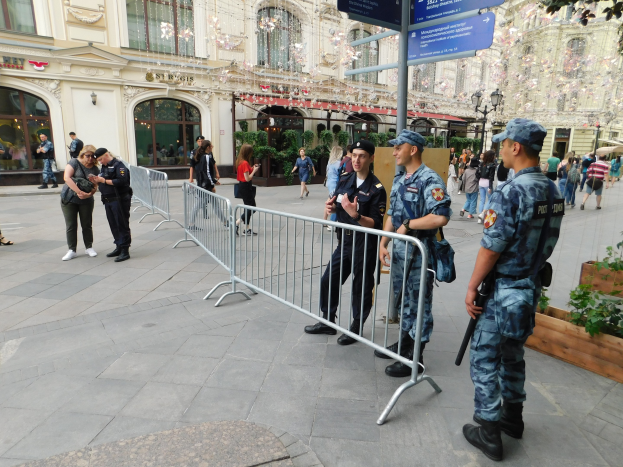 Polizeibeamte in Uniform stehen hinter Barrieren und blicken auf eine Menge, von der einige Kappen tragen und Feuerwaffen halten, während einer Anti-Terror-Operation in Wien, Österreich.