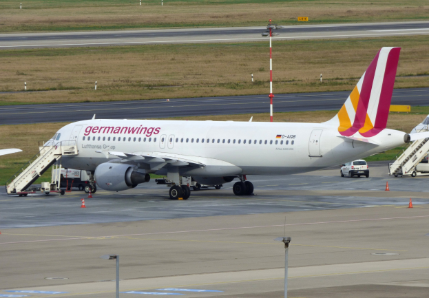 Germanwings Airbus A320-200 am Frankfurt Airport mit Bodenfahrzeugen, Verkehrskegeln, Versorgungsmasten und Grasfläche im Hintergrund geparkt.
