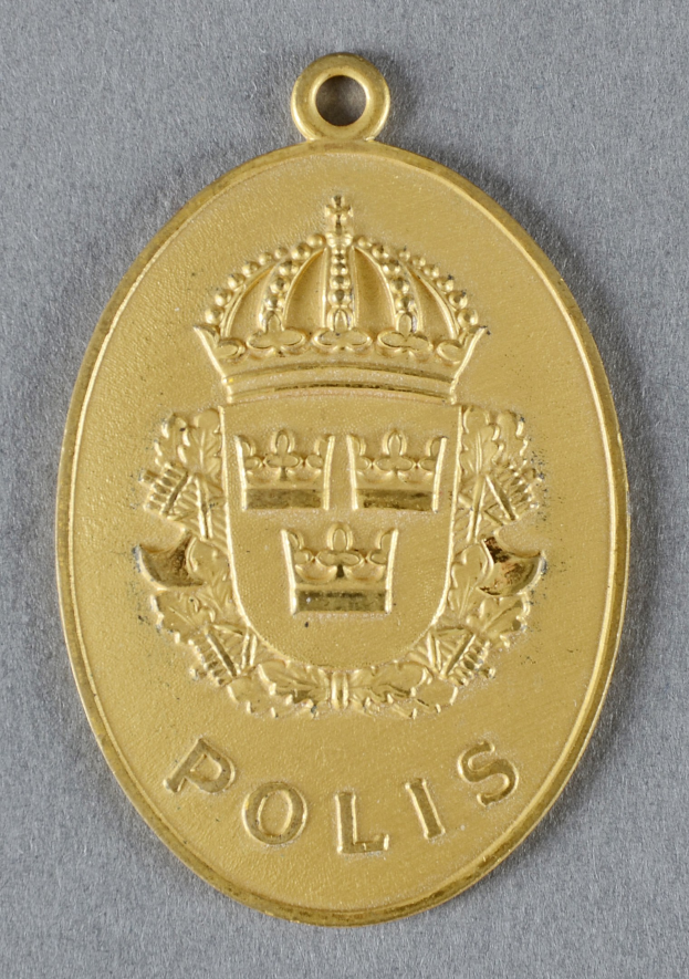 Goldene Medaille mit einer Krone, die wie ein Polizeistern aussieht, in der Mitte des Bildes mit eingravierter Inschrift.