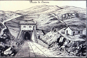 Eine Schwarz-Weiß-Zeichnung eines Tunnels in den Bergen mit einer Bahnschiene, Häusern auf beiden Seiten und Hügeln im Hintergrund, mit Text oben.