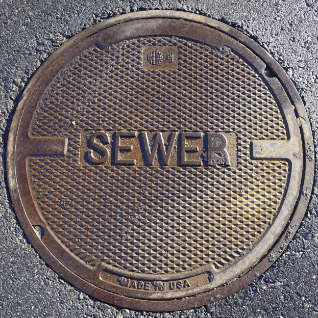 Metallschachtdeckel auf der Straße mit der geprägten Aufschrift "Kanal"