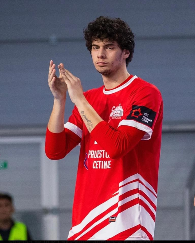 Ein Mann in rot-weißem T-Shirt klatscht in der Vordergrund mit einer anderen Person und einer Wand im Hintergrund, und Text unten lesend "Copenhagen Futsal Club - Foto 1".