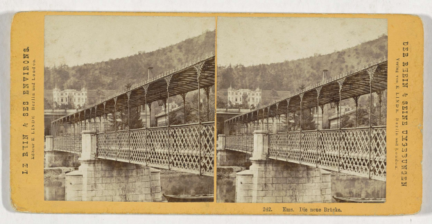 Schwarz-weiß-Fotografie einer Brücke, die einen Fluss in Leipzig überquert, mit Gebäuden, Bäumen und einem Hügel im Hintergrund.