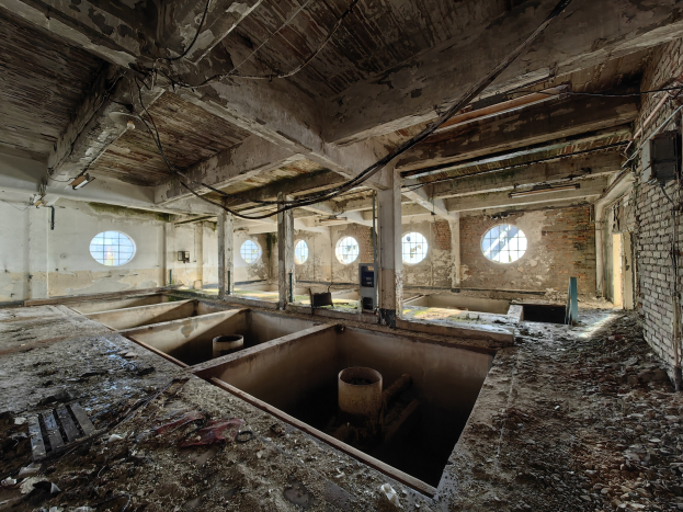 Verlassener Gebäuderaum im Chernobyl-Ausschlussgebiet mit verstreuten Trümmern, freiliegenden Wänden, Decke und strukturellen Elementen.