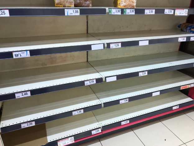 Leere Supermarktregale in einer Reihe mit sichtbarem Boden darunter.