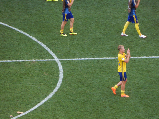 Mannergruppe in Fußballtrikots klatscht auf einem Feld nach einem Spiel.