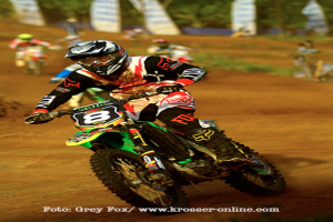 Mehrere Personen bei Motorradrennen, alle mit Helmen, mit Text am Bildrand.