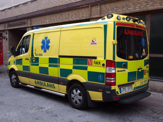 Ambulanz vor einem Backsteinbau mit Text geparkt, mit einem Feuerlöscher auf der linken Seite.
