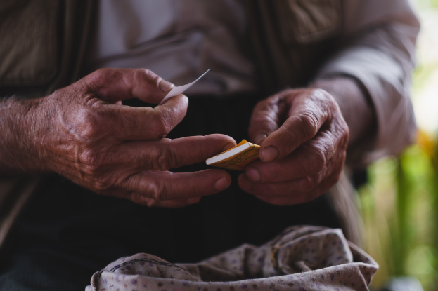 Alter Mann hält ein Blatt Papier, sieht besorgt aus mit unscharfem Hintergrund, möglicherweise aufgrund von Demenz.
