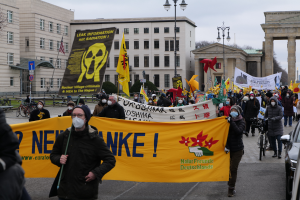 Eine große Gruppe von Menschen marschiert auf einer Straße, hält Schilder und Fahnen, während sie an einer Demonstration gegen Kernenergie in Deutschland teilnimmt.