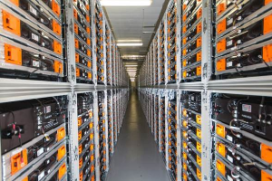 Eine lange Reihe von Servern in einem Rechenzentrum mit elektronischen Geräten in den Gestellen und Leuchten oben.