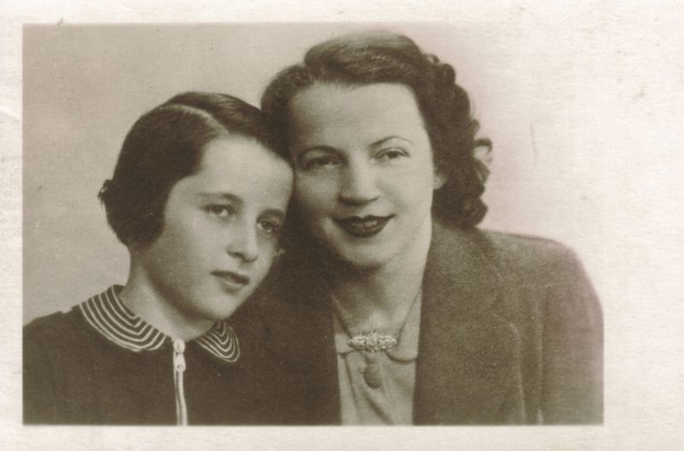 Ein altes Schwarz-Weiß-Foto von einer Mutter und Tochter, die fröhlich in die Kamera schauen.