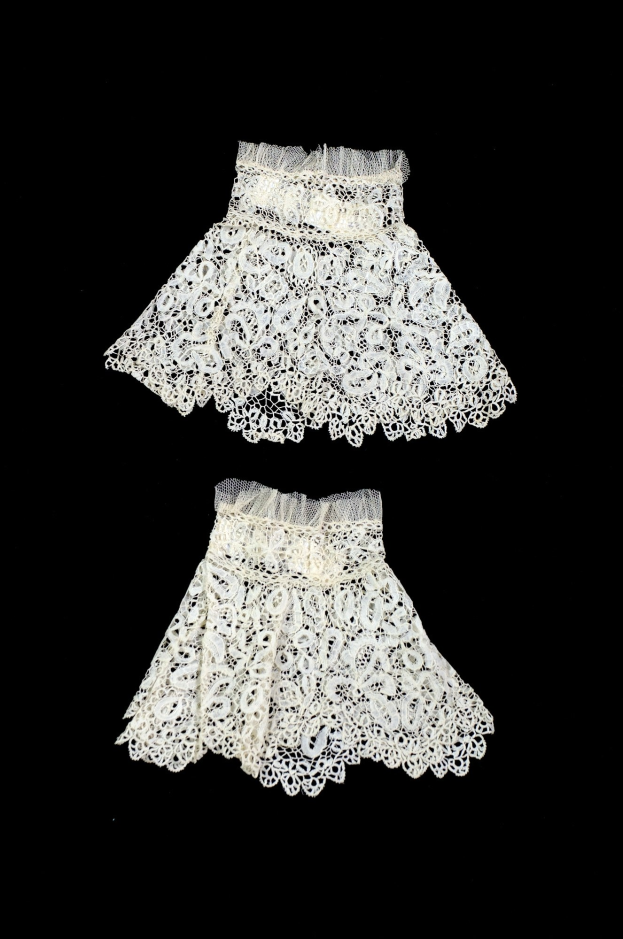 Zwei weiße Spitzenröcke mit zarten Mustern auf schwarzem Hintergrund.