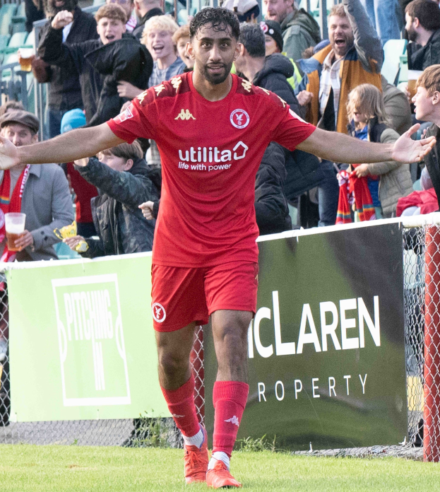 Ein Fußballspieler in roter Uniform rennt mit ausgebreiteten Armen auf einem Feld während eines Matches zwischen Middlesbrough FC und Swansea City in der Sky Bet Championship, während Zuschauer von hinter einem Zaun zusehen.