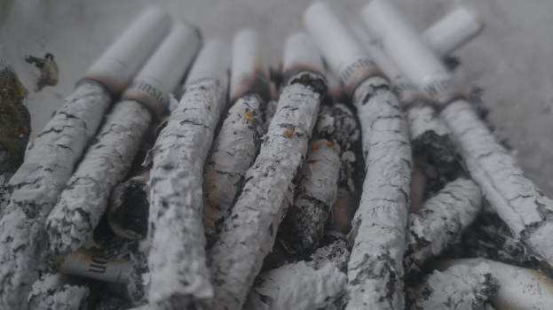 Ein unordentliches Häufchen aschfarbener Zigaretten auf einem Tisch.