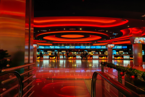 Ein Casino-Innenraum mit einem Weihnachtsbaum in der Mitte, gefliestem Boden, Geländern auf beiden Seiten, verzierten Säulen und Deckenbeleuchtung, mit Menschen im Hintergrund, die eine festliche Atmosphäre schaffen.