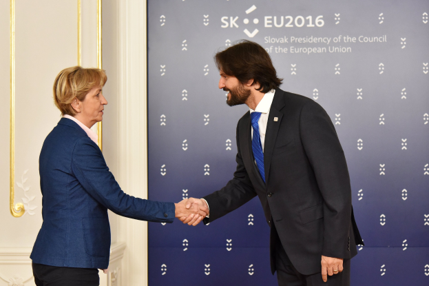 Bundeskanzlerin Angela Merkel und Joachim Gauck schütteln sich die Hände vor einem "EU-Gipfel"-Plakat, freundlich lächelnd.