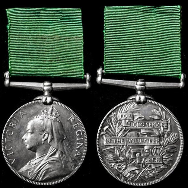 Zwei silberne Medaillen mit grünen Bändern, eine mit einer Personendarstellung und die andere mit eingravierter Schrift, vor schwarzem Hintergrund, von der Langen Dienstzeit in der Freiwilligen Force.