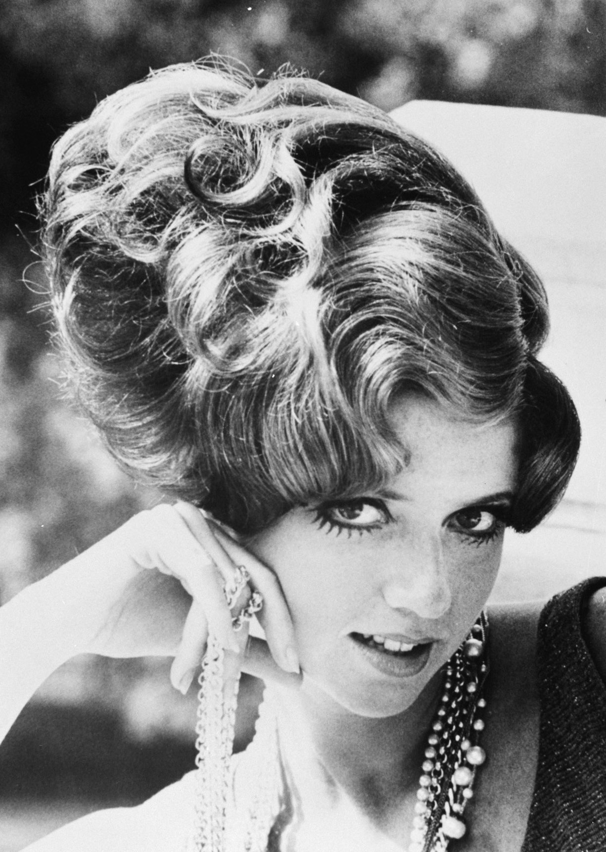 Schwarzes und wei├čes Foto von Prinzessin Diana in einem Kleid und Schmuck mit einem unscharfen Hintergrund.