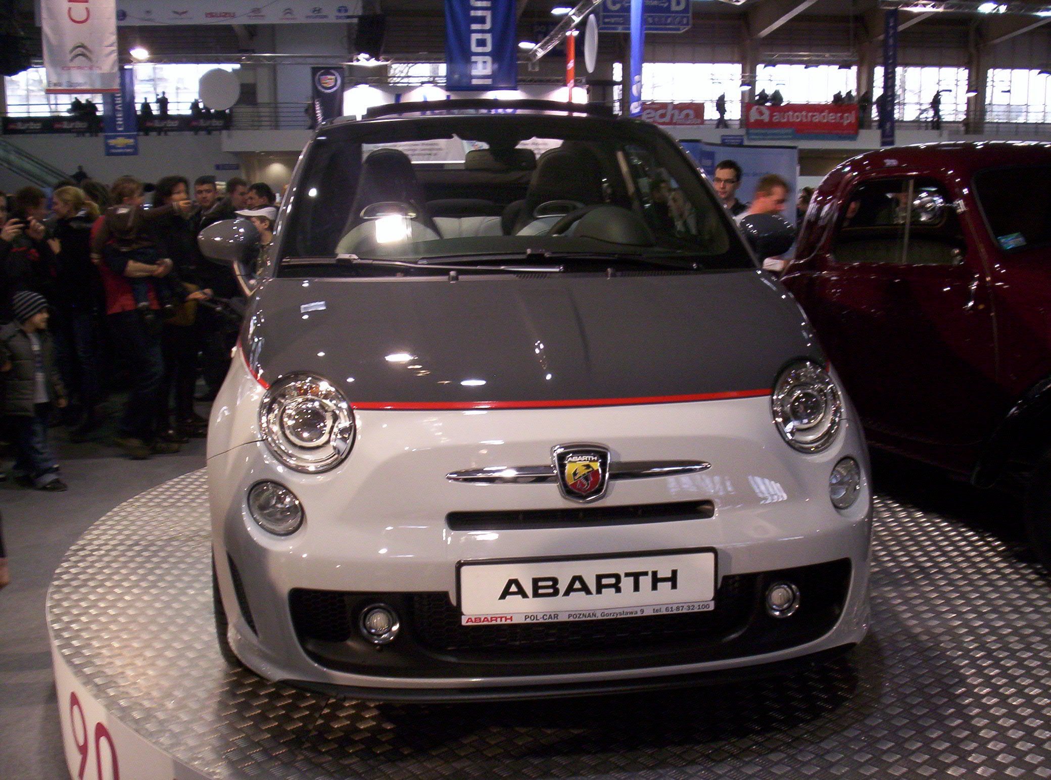 Ein roter und schwarzer Fiat 500 Abarth auf einer Autauschstellung.